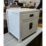 A small Chinese ivory lacquered cabinet, the single drawer over two cupboard doors with brass