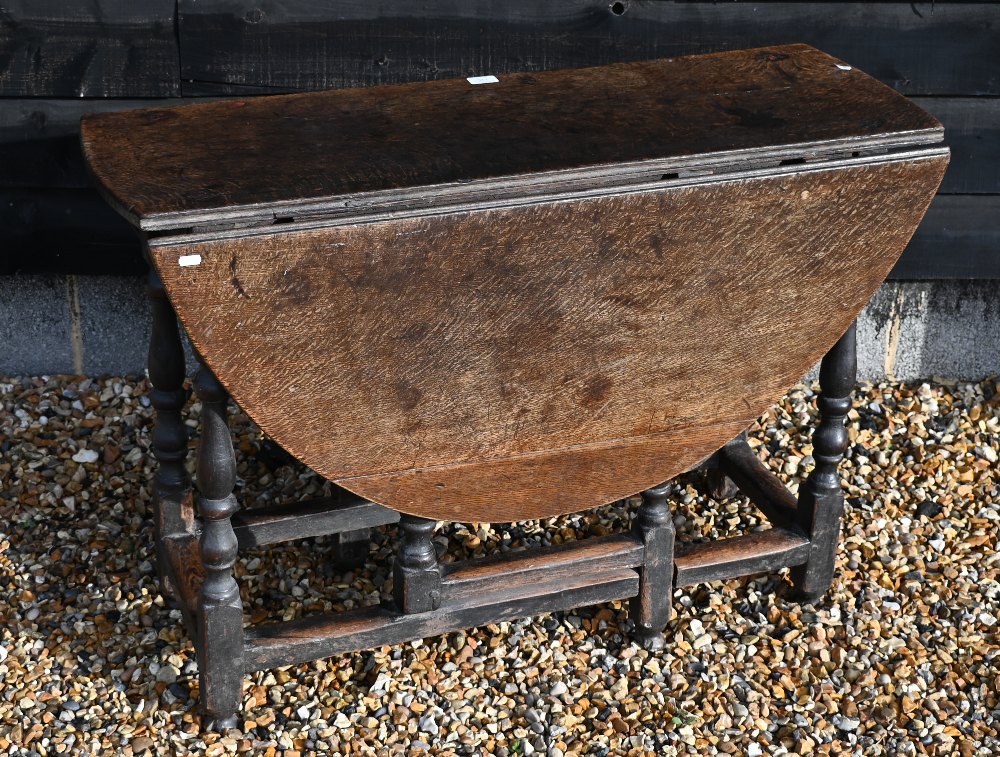 An 18th century oak drop leaf dining table on gate-leg action turned supports