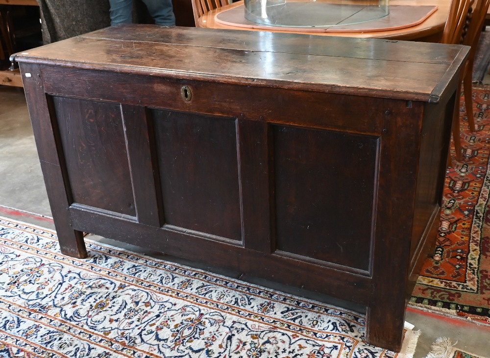 A large antique panelled oak coffer, hinged top enclosing the deep storage area, 138 cm wide x 56 cm