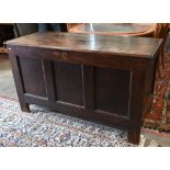 A large antique panelled oak coffer, hinged top enclosing the deep storage area, 138 cm wide x 56 cm