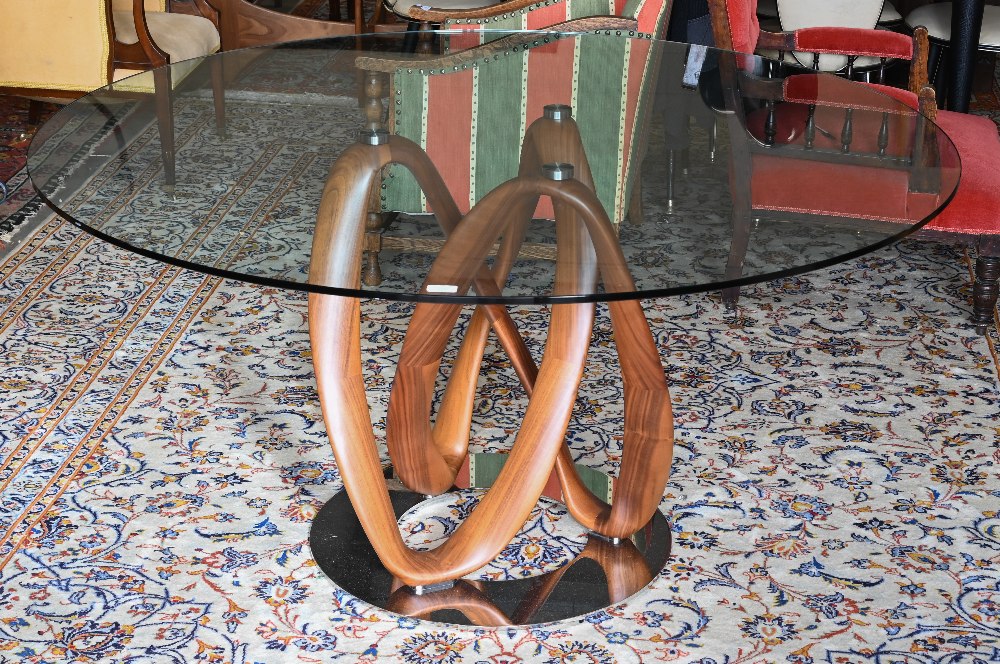 An Italian Porada Infinity dining table with circular glass top on an American walnut Mobius loop