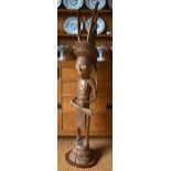 A large Oceanic carved wood figure of a tribesman with extravagant winged headdress, necklace and