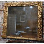 A 18th century bacchanalian style giltwood and gesso frame fitted with a faux mirror comprised of