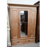 A pitch pine wardrobe with panelled front centred by mirrored door over single drawer base, 140 cm