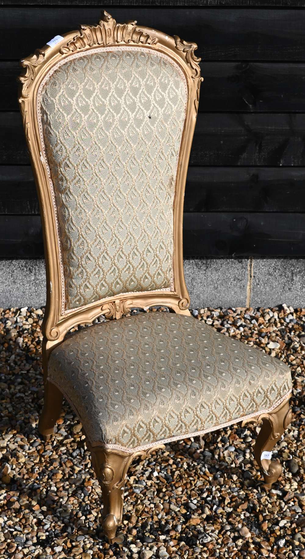 A Continental gilt framed nursing chair with repeating leaf pattern brocade upholstery
