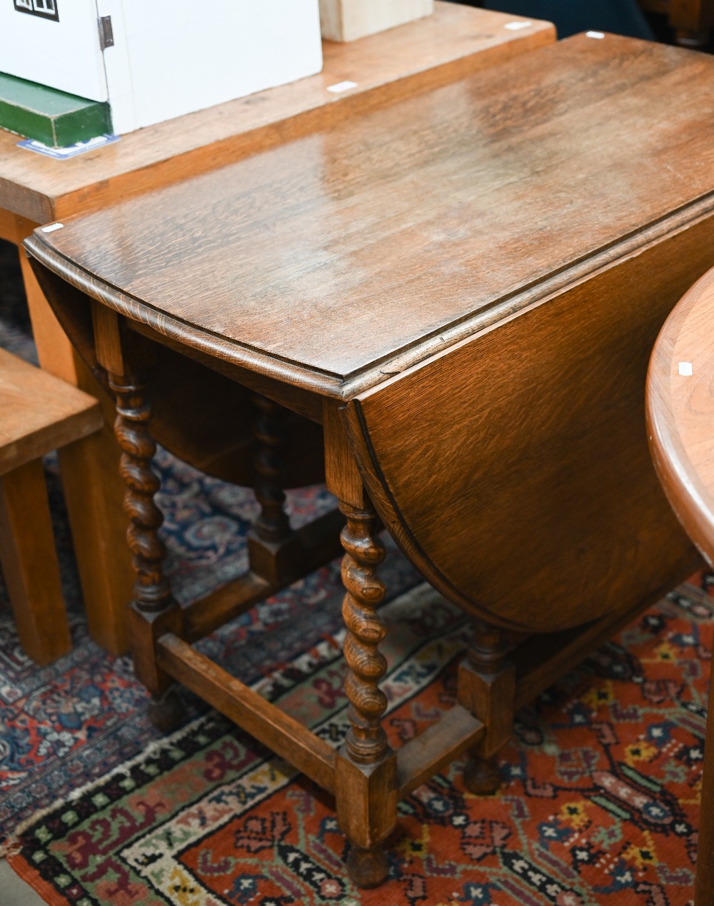 An early 20th century oak drop-leaf dining table on gateleg action with barley twist supports