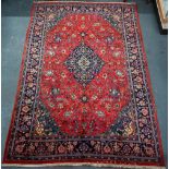 A Persian Sarouk carpet, the red ground centred by a blue ground medallion radiating floral vines,