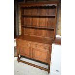 A traditional oak high dresser, the open rack over two short drawers and pair of cupboards, on