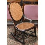 An antique oak framed rocking chair with cane worked back and seat