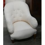 A low button back bedroom armchair with cream upholstery