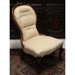 A Victorian mahogany floral carved nursing chair with button back damask upholstery
