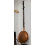 An antique engraved copper warming pan with turned mahogany handle