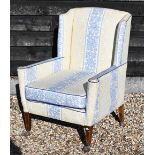 An Edwardian mahogany framed wingback armchair with traditional pale yellow and blue foliate