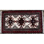 A Persian Belouch rug, the geometric design on cream ground within repeating brown/red borders,