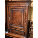 An antique oak wall cabinet with panelled cupboard enclosing two shelves over single drawer, 74 cm