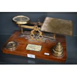 An antique brass set of postage scales on teak base, with weights 33 cm wide