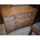 An antique pine chest of two short over two long drawers with turned pulls, standing on shaped