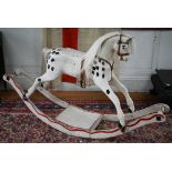 An antique painted pine rocking horse with glass eyes and leather fittings, on rocker, overpainted