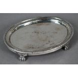 Regency oval silver tea pot stand with engraved decoration, gadrooned rim and paw feet, maker's mark