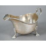 Silver sauce boat in the Georgian manner, with beaded rim and scroll handle, on three shell feet,