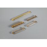 A long 9ct yellow metal bar brooch, 7.5 cm; two 9ct rose gold safety pin brooches; and two