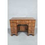 A Georgian style feather-banded walnut kneehole desk, with an arrangement of nine drawers around a