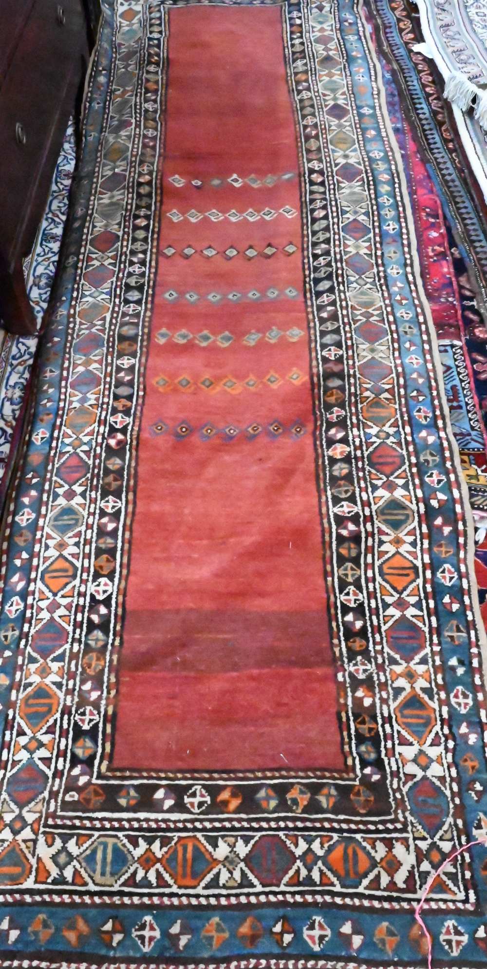 An antique Persian Hamadan rust-red ground runner, the stylised boteh within multi-coloured borders,