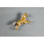 An 18ct yellow and white gold brooch in the form of a galloping stallion, with textured body and