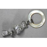 An Edwardian silver baby's rattle with mother of pearl teething ring, hung with teddy bear and