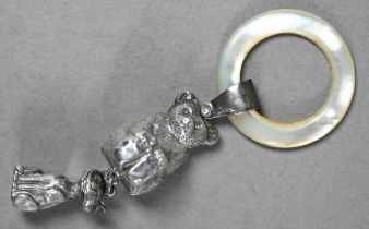 An Edwardian silver baby's rattle with mother of pearl teething ring, hung with teddy bear and