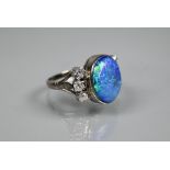 An opal and diamond ring, the large opal of blue iridescence with three diamonds to each side, white
