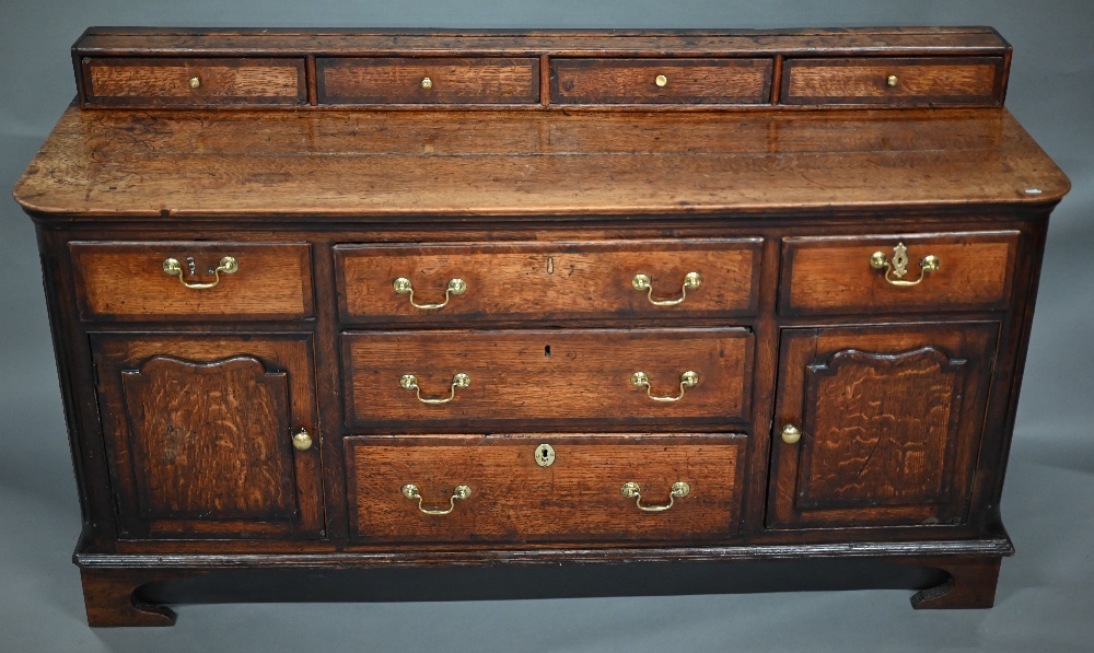 A 18th century oak low dresser, the two plank top with four drawer stage back, over an arrangement