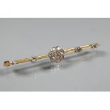An early 20th century bar brooch featuring a central diamond set daisy cluster, with two further