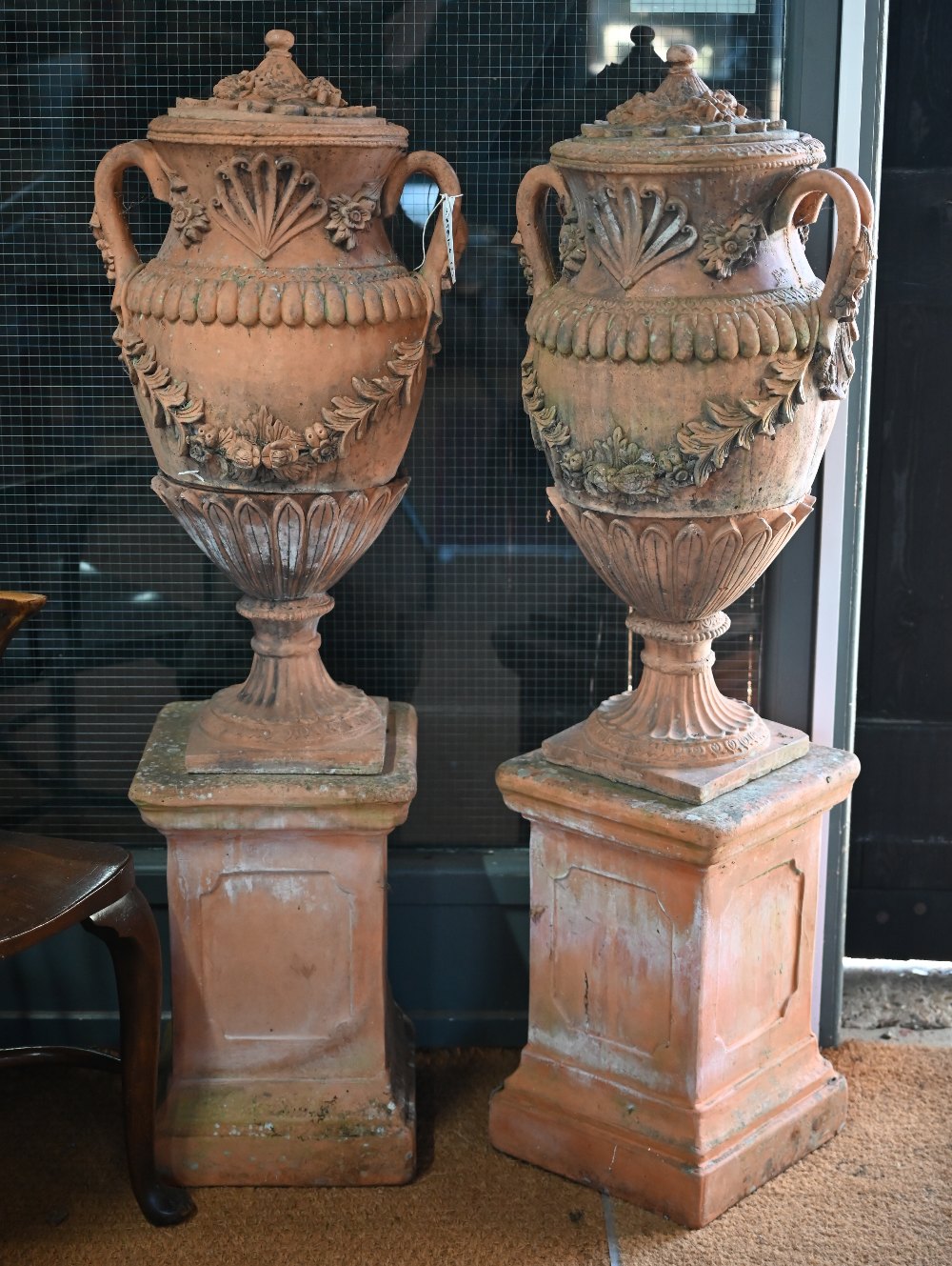 A large pair of weathered classical cast terracotta lidded urns, with twin loop handles and