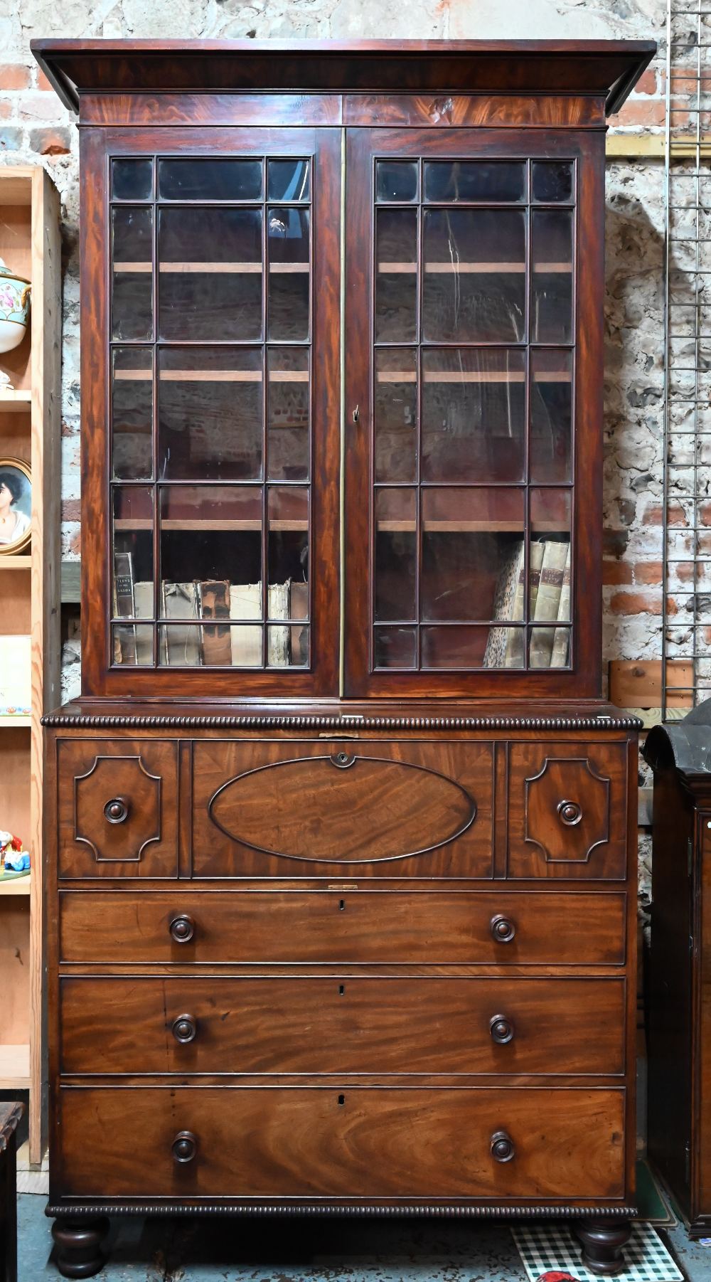 A Regency mahogany secrétaire library bookcase, the associated two door astragal glazed cabinet