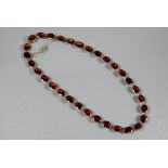 A Victorian oval garnet set necklace in 9ct yellow gold closed back setting, concealed clasp with