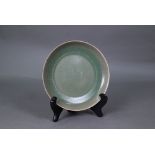 A Chinese celadon dish with combed exterior, covered in a crackled olive green glaze thinning in