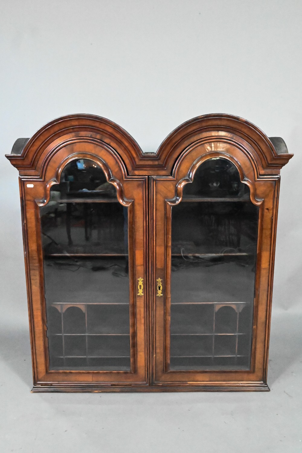 A William & Mary period walnut double dome top cabinet, with pair of arched glazed doors enclosing