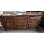 An 18th century oak low dresser, the three plank top over an arrangement of five drawers and two