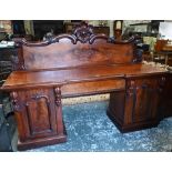 A large Victorian mahogany country house twin pedestal sideboard, the heavily moulded back over a
