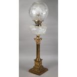 A late 19th century brass Corinthian column style cast oil lamp with clear cut-glass reservoir and