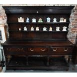 A Georgian oak three drawer dresser, with associated rack (reduced in height), with planked pot