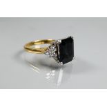 An Art Deco style ring set with rectangular dark blue sapphire (probably), with triple diamond set