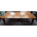 A large Victorian golden oak extending table, the wind action top with rounded corners accepting the