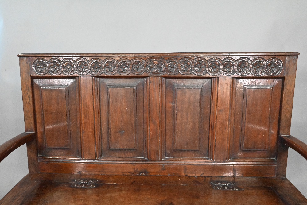 An antique oak box settle, the panelled back with floral carved rosette's over shaped arms and an - Image 4 of 6