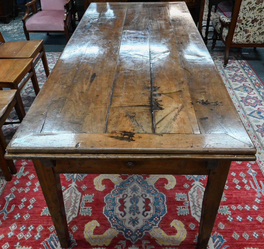 An antique French fruitwood extending draw leaf dining table, with frieze drawer to one end,