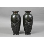 A pair of Japanese base metal vases cast in high relief with fierce three-clawed dragons,