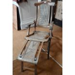 An Edwardian beech framed folding steamer chair, with caned panels and foot extension