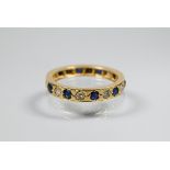 A sapphire and diamond full eternity ring, the alternating stones set within unmarked yellow metal
