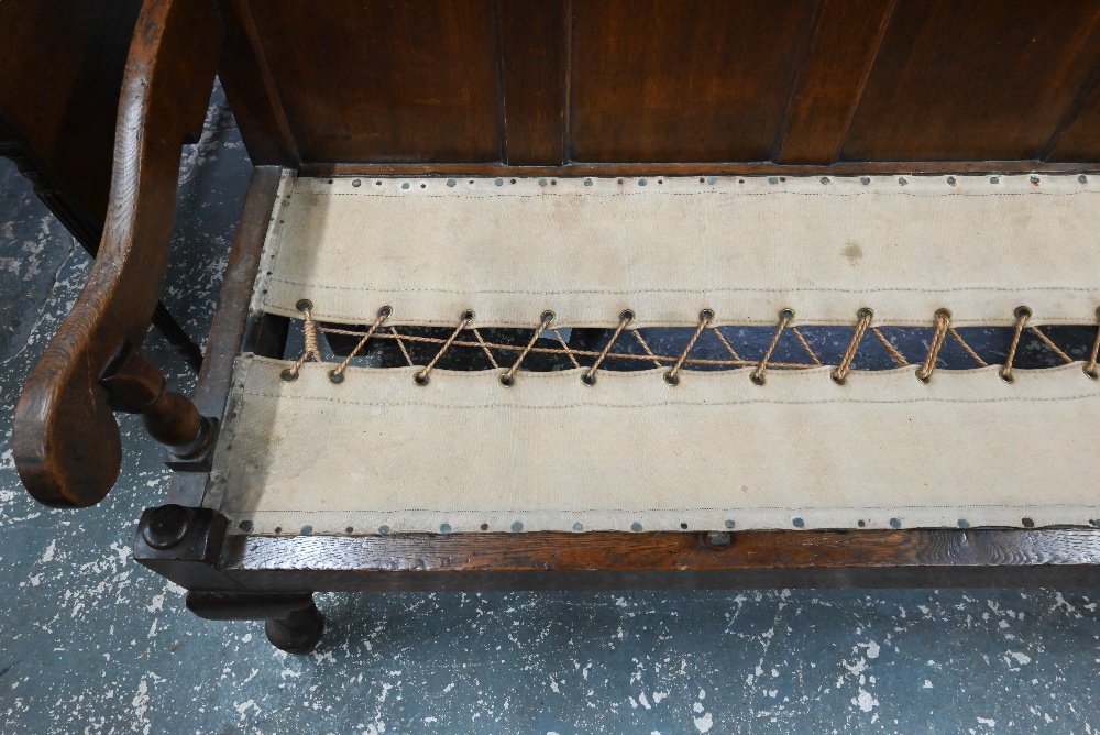 An 18th century oak panel backed settle, with shaped arms over a rope and canvas seat (cushion - Image 3 of 6